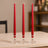 Three red taper candles in glass holders on a table.