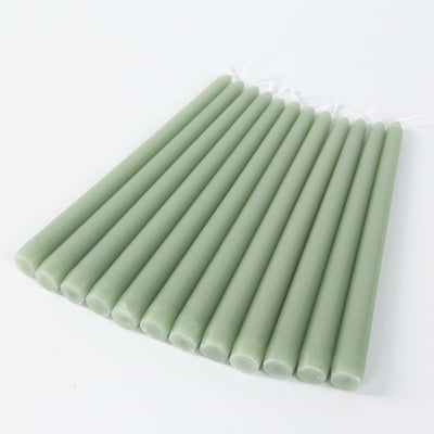 Green taper candles arranged in a row on a white background.