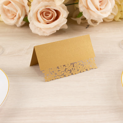 Gold laser-cut place card on a table with floral decor.