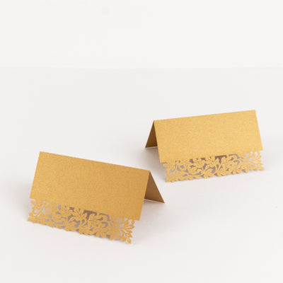 Gold place cards with intricate lace design on a white background.