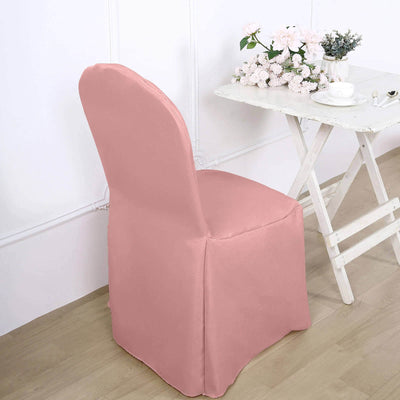 Pink chair cover draped over a chair beside a table with flowers.