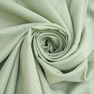 Light green fabric rolled in a spiral pattern, showcasing its smooth texture.