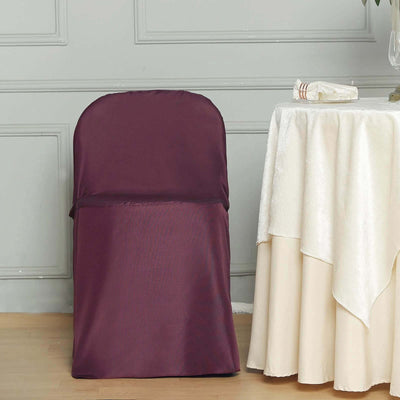 Burgundy chair cover draped over a chair next to a table with a cream tablecloth.