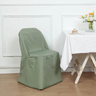 Green chair cover draped over a dining chair beside a table with flowers.