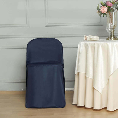 Navy blue chair cover draped over a simple chair beside an elegant table setting.