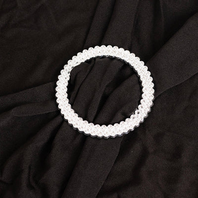 Clear beaded circular hair accessory on a black fabric background.