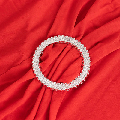 Silver beaded circular hair accessory on red fabric.