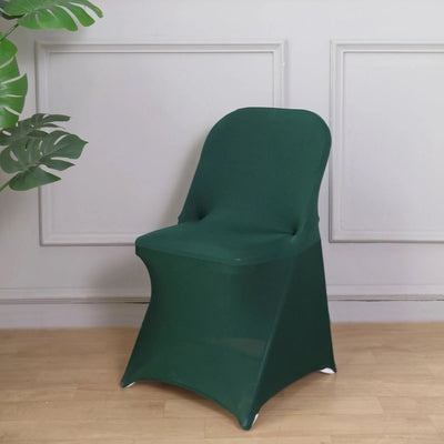 Green stretch chair cover on a wooden floor with a plant backdrop.