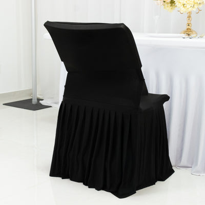 Black chair cover with pleated skirt on a plain backdrop.