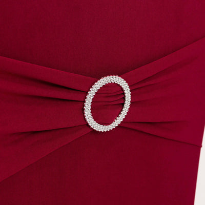 Burgundy dress detail featuring a sparkling oval brooch embellishment.