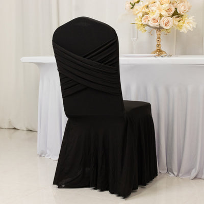 Black chair cover with draped design, set against a white table and floral arrangement.