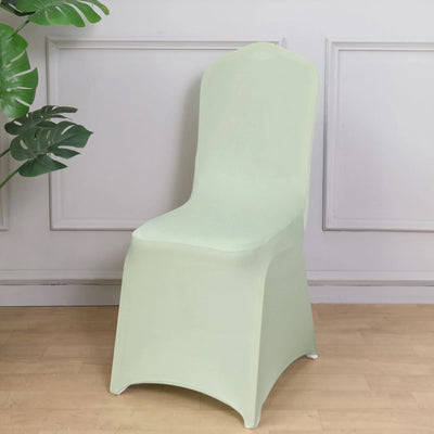 Green chair cover on a wooden floor with a plant backdrop.
