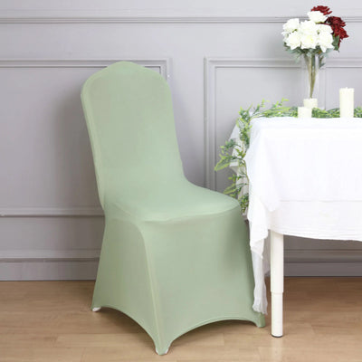 Green chair cover draped over a chair beside a table with flowers and candles.