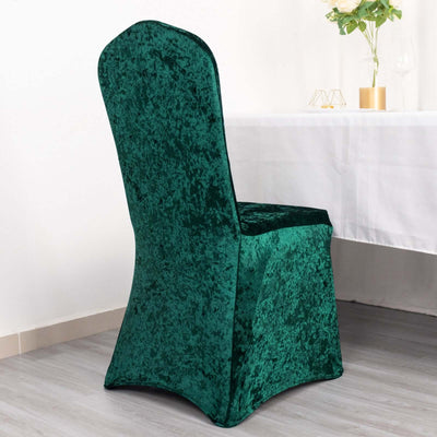 Green velvet chair cover on a dining chair against a plain backdrop.