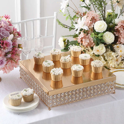 Elegant dessert display with cupcakes on a gold tray, adorned with flowers.