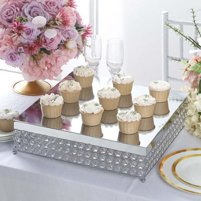 Elegant mirrored cake stand with decorative cupcakes and floral arrangements.