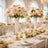 Elegant floral centerpieces in crystal vases for a wedding reception table setting.