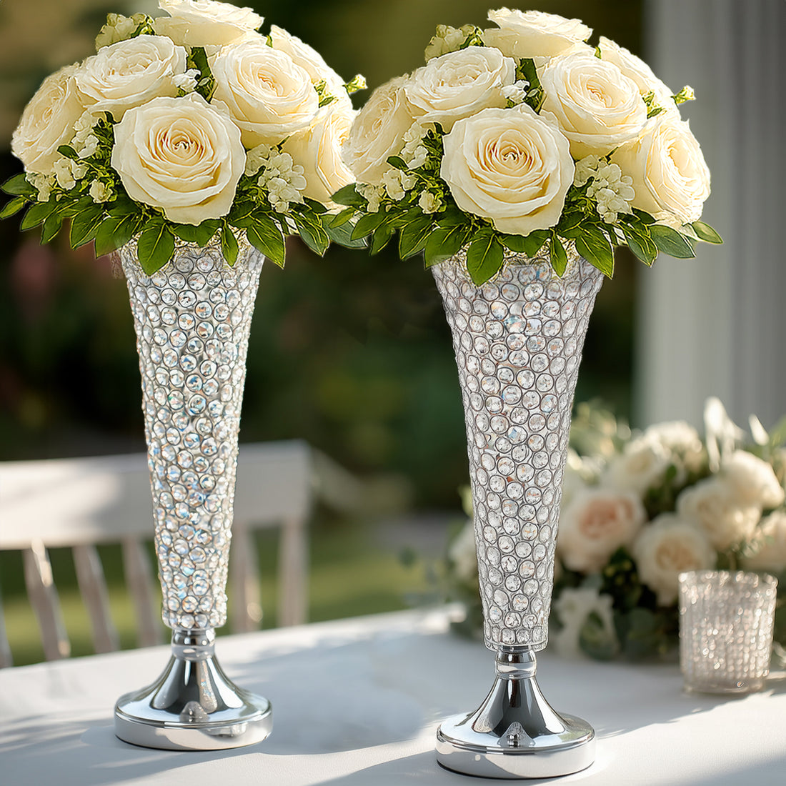 Elegant crystal vases with white roses and greenery arrangement.