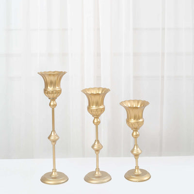 Gold decorative candle holders in varying heights on a white background.