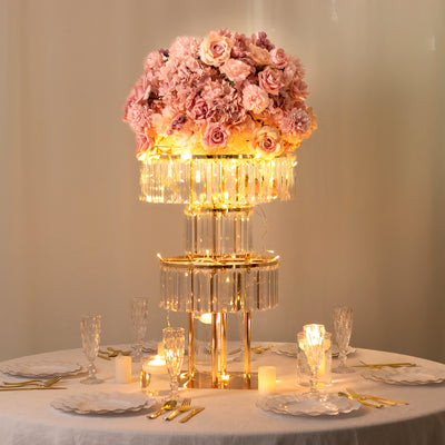 Elegant floral centerpiece with pink roses and lights on a dining table.