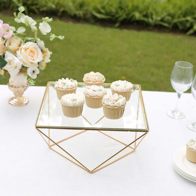 Elegant glass display with six decorated cupcakes at an outdoor event.