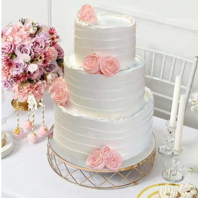 Elegant three-tier wedding cake adorned with pink roses on a decorated table.