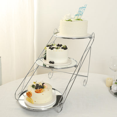 Three-tier cake stand with assorted decorated cakes on a table.