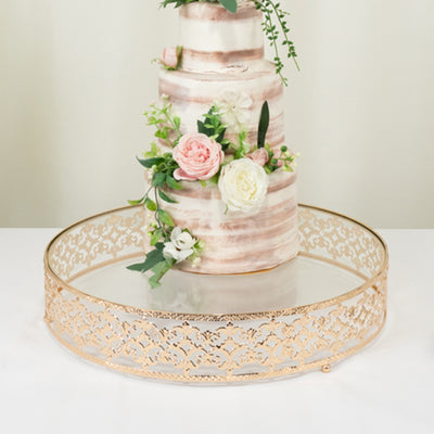 Gold decorative cake stand with intricate design and glass top.
