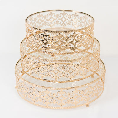 Gold decorative trays with intricate lace design, stacked on a white background.