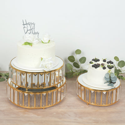 Elegant birthday cakes displayed on decorative cake stands with greenery accents.