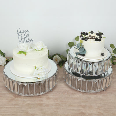 Elegant birthday cakes on decorative mirrored stands with floral accents.