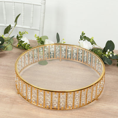 Gold and crystal decorative tray on a wooden table with greenery.