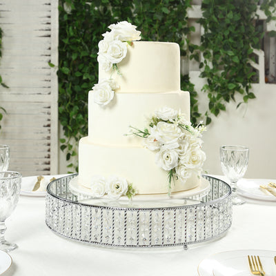 Elegant three-tier white wedding cake adorned with roses on a decorative stand.