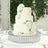 Elegant three-tier white wedding cake adorned with roses on a decorative stand.