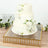 Elegant three-tier wedding cake adorned with white roses on a decorative tray.