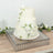 Elegant three-tier wedding cake adorned with white roses on a mirrored tray.