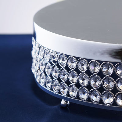 Silver cake stand with crystal embellishments on a dark surface.