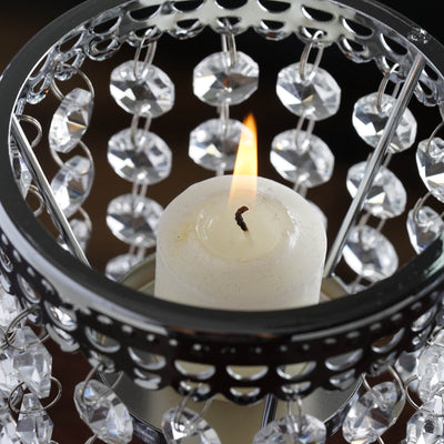 Candle in decorative holder with crystals, glowing flame.