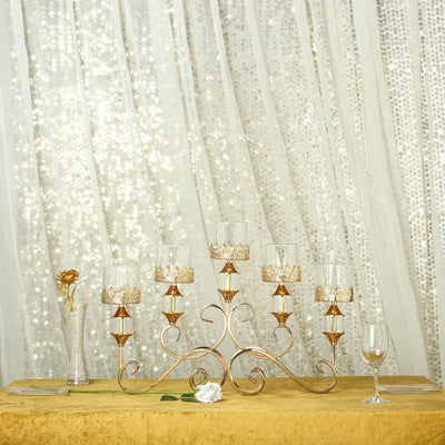 Elegant gold candle holder with glass votives on a shimmering backdrop.