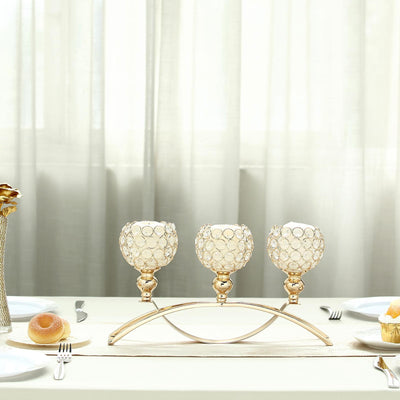 Elegant gold candle holder with three glass globes on a dining table setting.