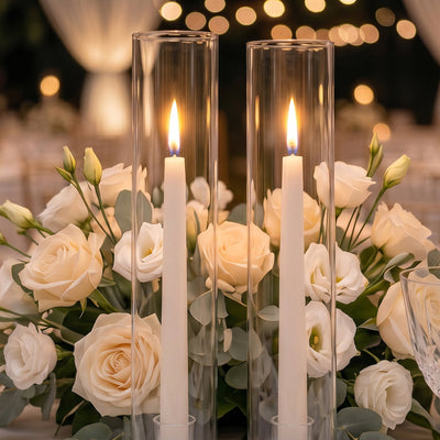 Elegant white rose centerpiece with candles in glass cylinders at a wedding table