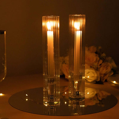 Elegant glass candle holders with lit candles on a reflective surface.