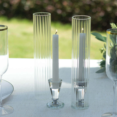 Elegant glass candle holders in various heights with white candles.