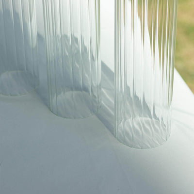 Clear ribbed glass vases on a table with natural light.