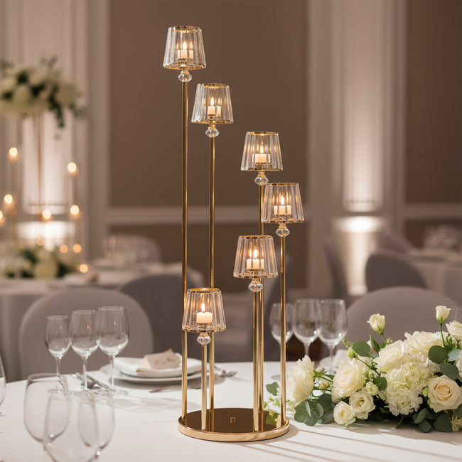 Elegant gold candle holder centerpiece with glass shades and candles at a wedding table.