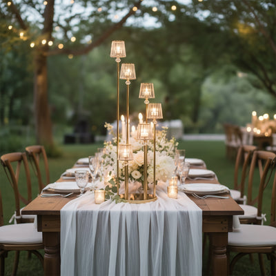 Elegant outdoor dining setup with candles and floral centerpiece in a garden setting.