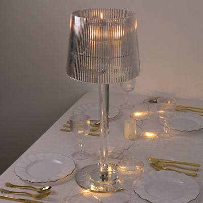 Elegant striped table lamp illuminating a dining setting with gold cutlery and glassware.