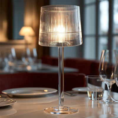 Elegant transparent table lamp with a pleated shade, illuminating a dining table setting.