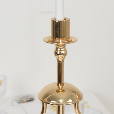 Elegant gold candlestick holder with a white candle on a plain background.