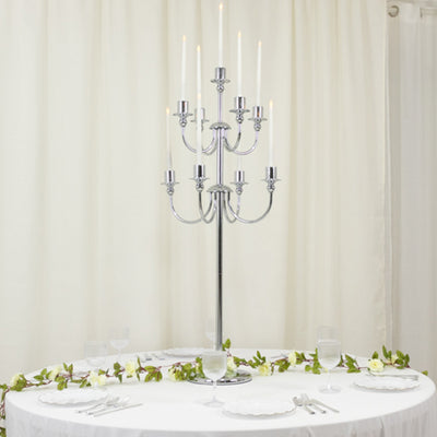 Elegant chrome candelabra centerpiece with candles on a round table.